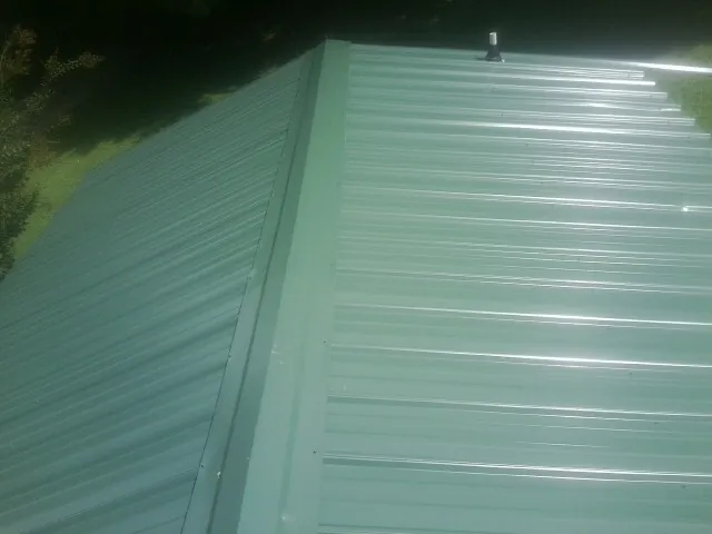 New green metal panels meeting at the ridge of a roof — Flat Roof Repair work by our crew in Cudahy