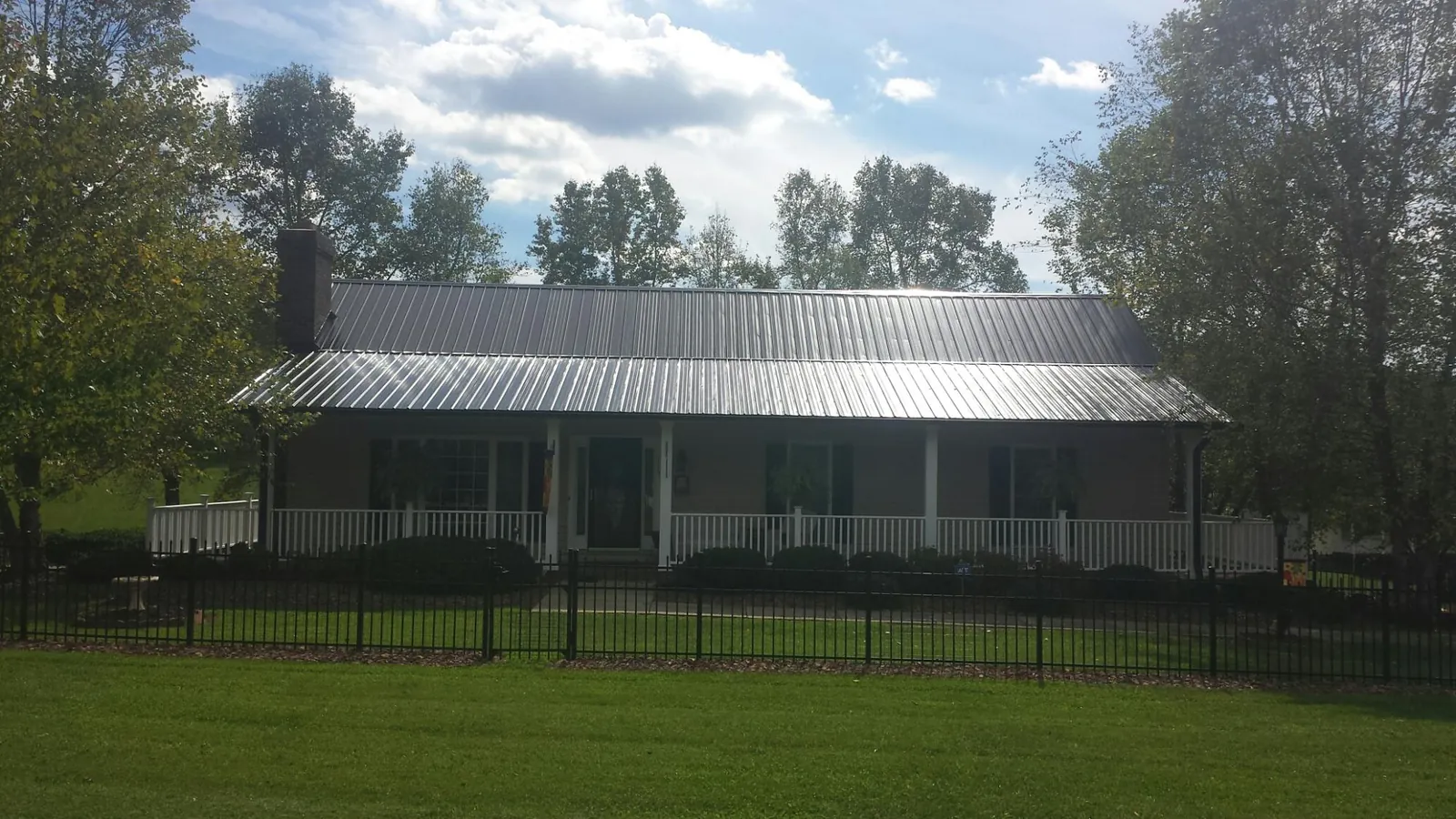 Gray metal roof on a brick ranch with a full width front porch — Gutter Guard Installation work by our crew in Cudahy