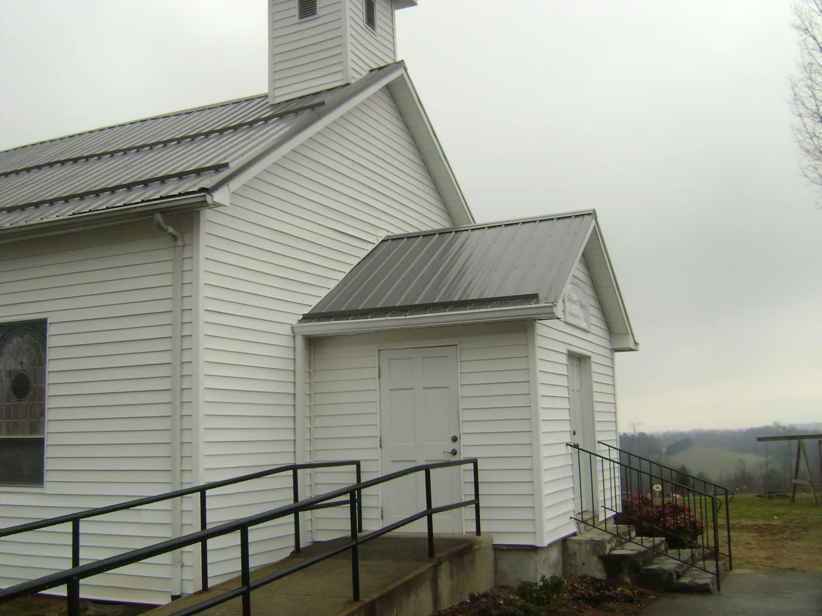 Gray metal roof on a white clapboard church with a steeple in Cudahy